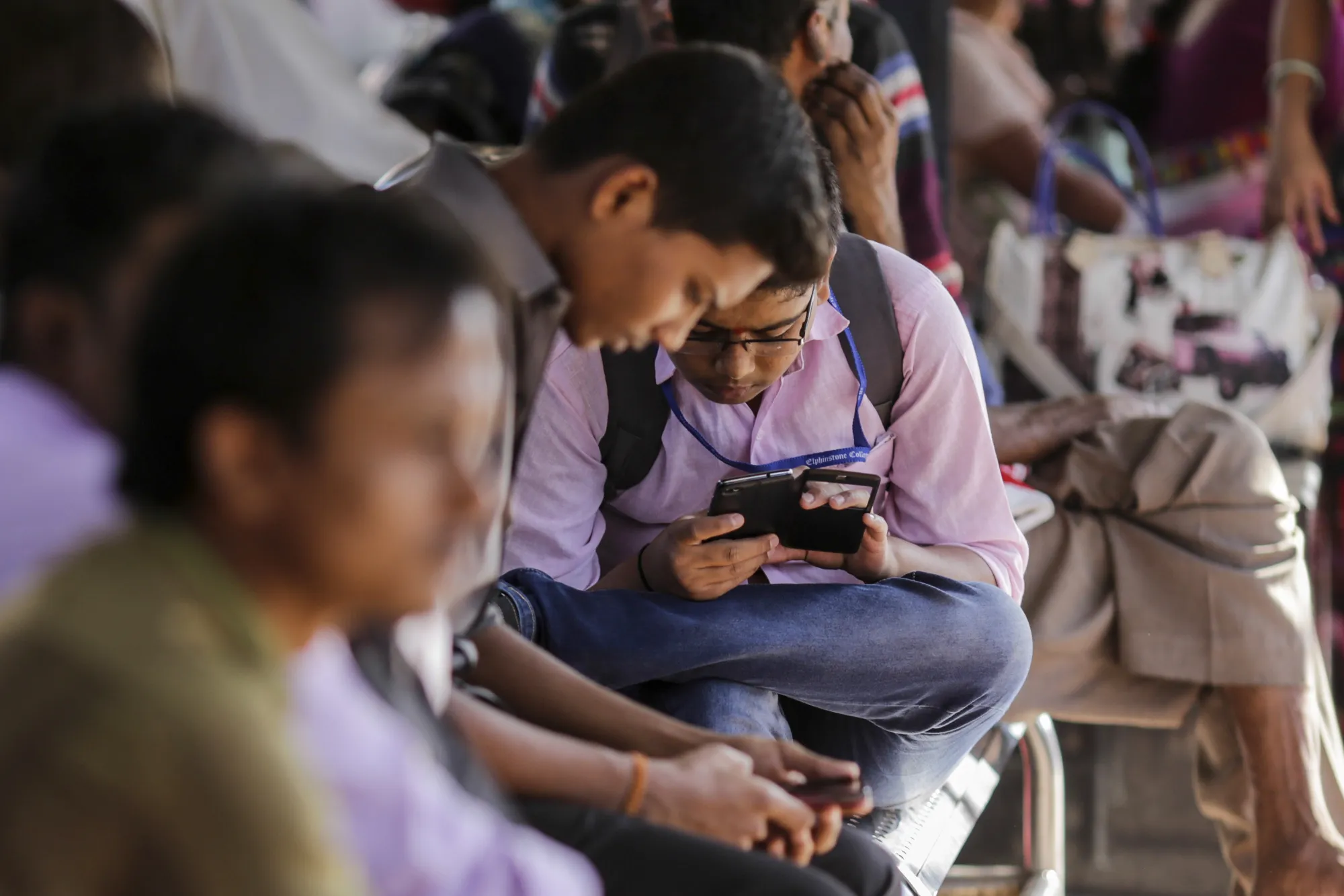 A passenger sits using a mobile phone at Mumbai Central Train Station in Mumbai, India.
