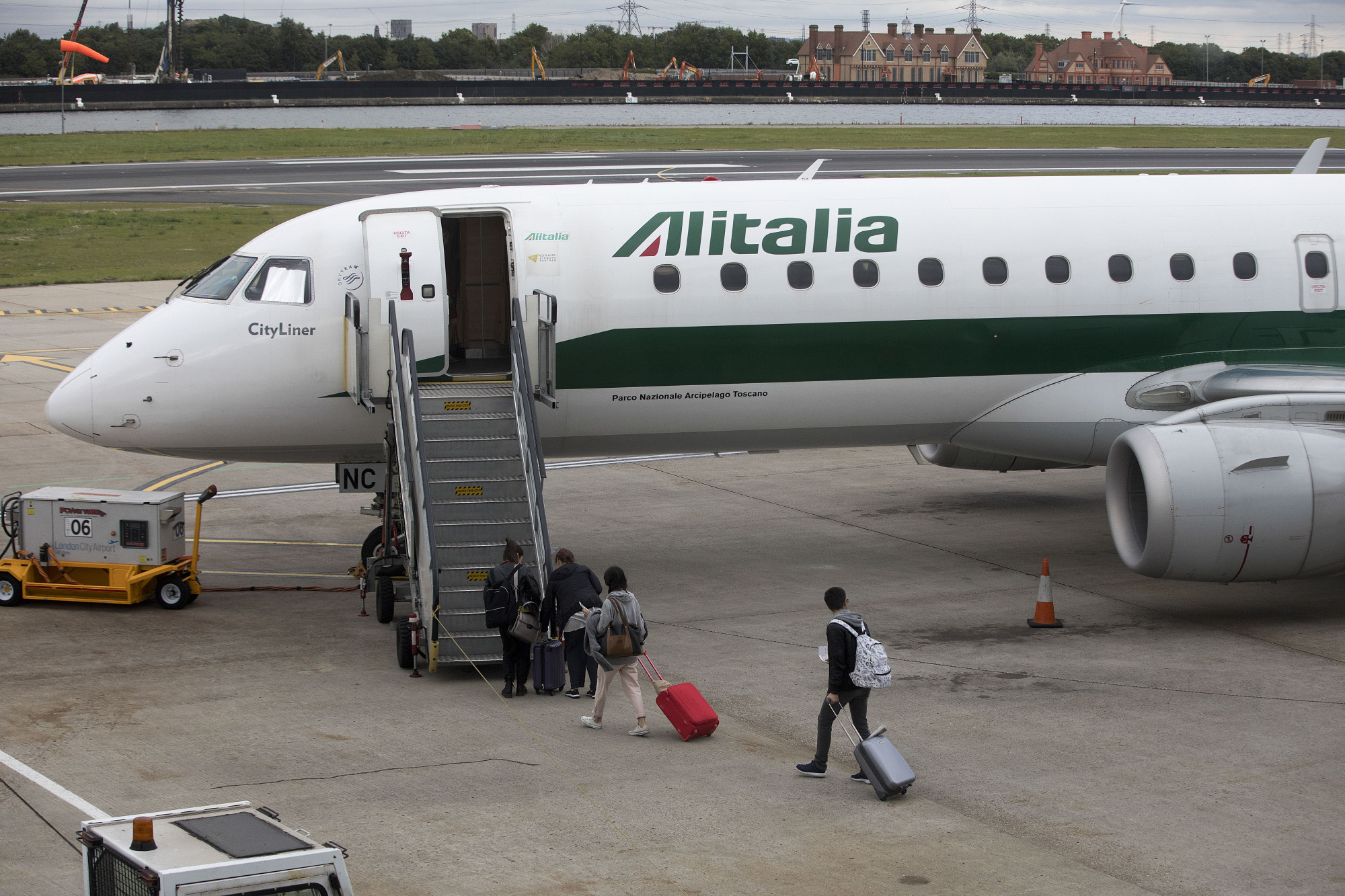 Passengers board a passenger aircraft, operated by Alitalia SpA,