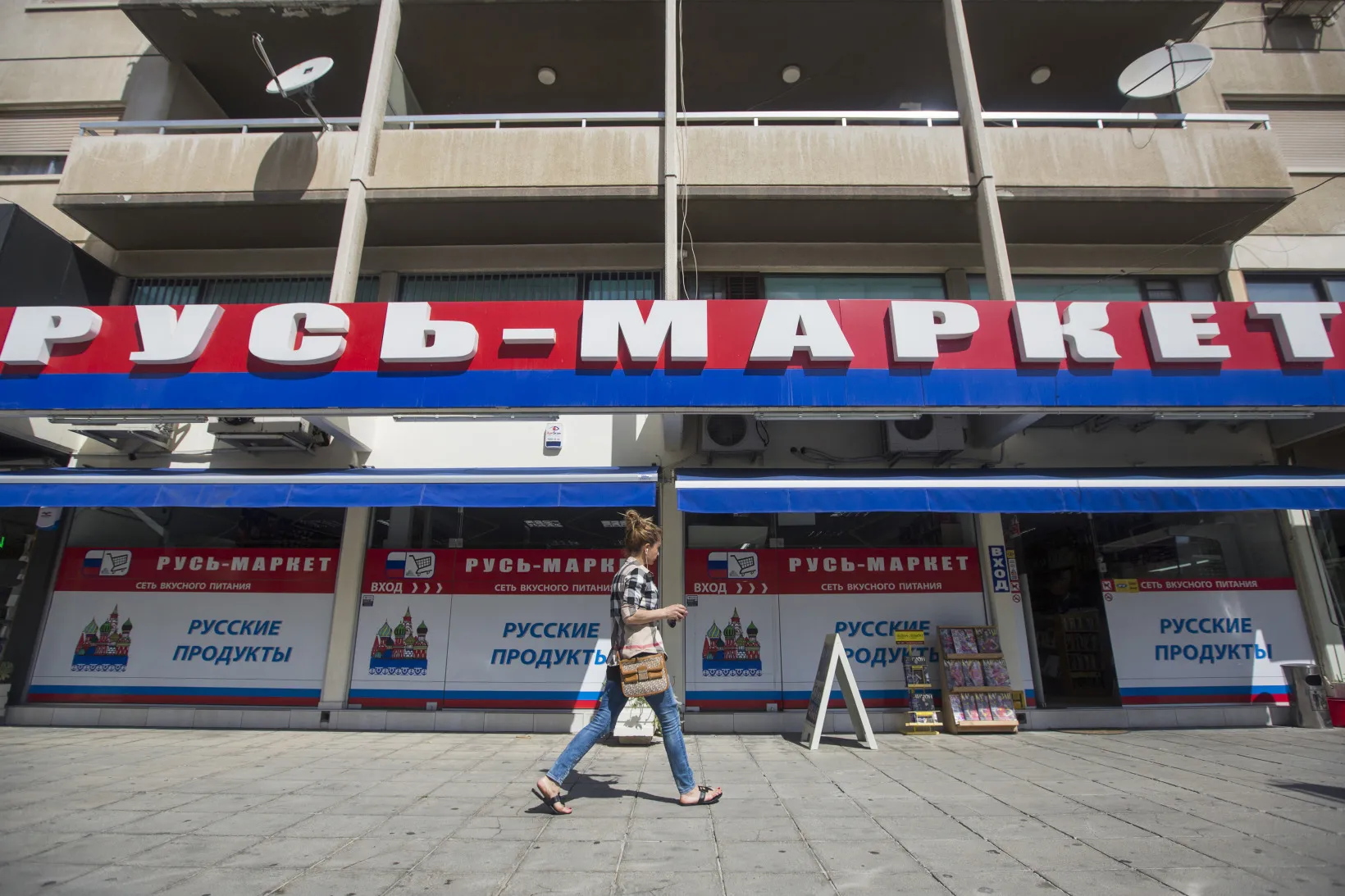 A pedestrian passes a Russian supermarket, branded in the colors of the Russian Federation, in Limassol.