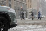 Pedestrians cross the street during a snowstorm in Chicago, Illinois, US, on Saturday, Nov. 29, 2025. Hundreds of flights have been canceled in and around Chicago and roads are becoming treacherous as one of the busiest travel weekends of the year collides with a major storm bringing wintery conditions throughout the US Midwest Saturday.