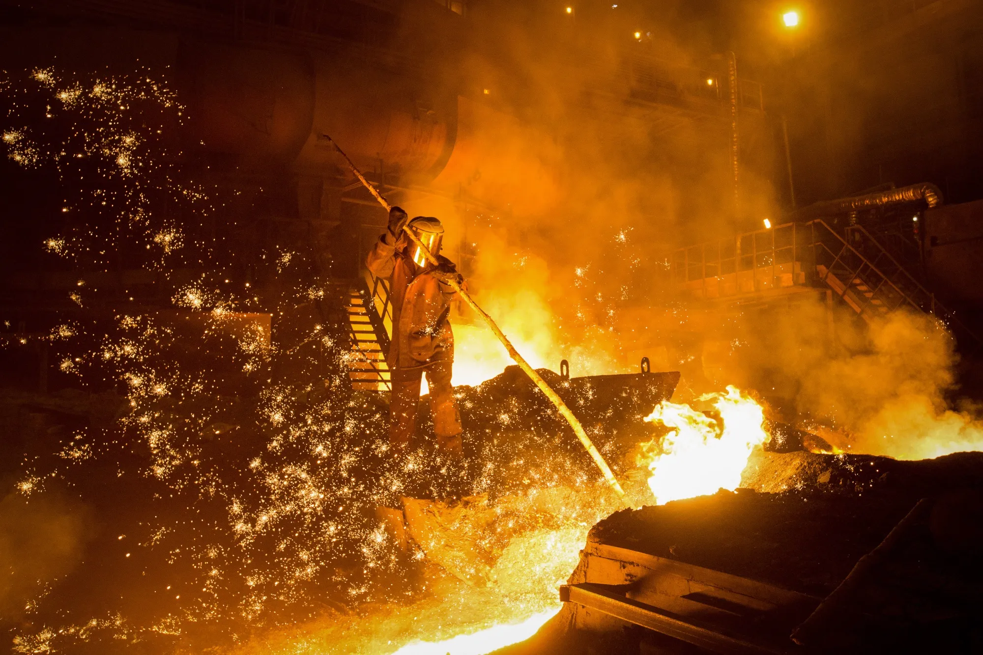 A worker supervises the flow of hot liquid metal&nbsp;from a&nbsp;blast furnace during&nbsp;smelting in Novokuznetsk, Russia.