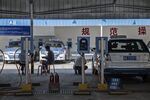Drivers sit on stools while BYD Co. E6 electric taxis sit charging at a charging station in Taiyuan, Shanxi province, China.