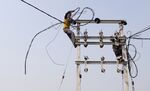 Workers connect electricity cables to a transmission pole during an implementation program by the Rural Electrification Corp. in the village of Manpur Kulchaura, Uttar Pradesh, India.
