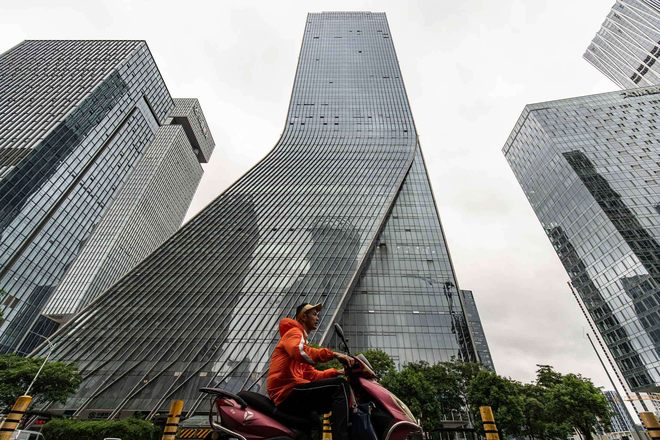 A man in Shenzhen rides past the tower that used to be Evergrande’s headquarters.