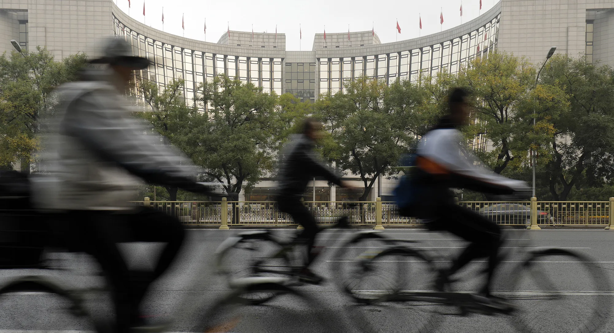 Cyclists ride past the People's Bank of China headquarters in Beijing.