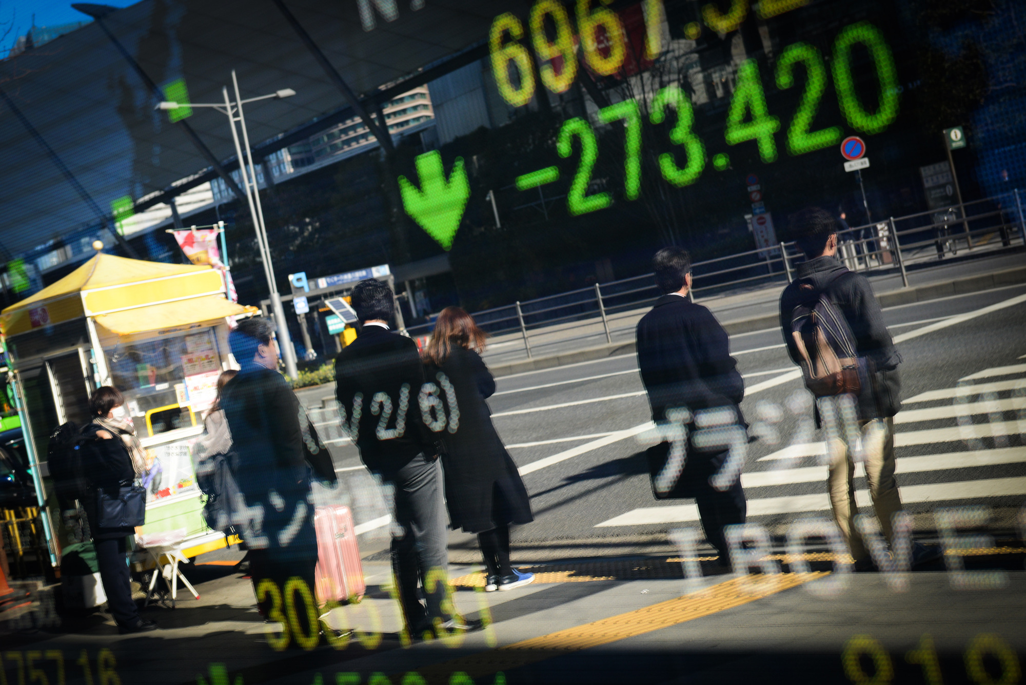Pedestrians are reflected in an electronic stock board outside a securities firm in Tokyo.
