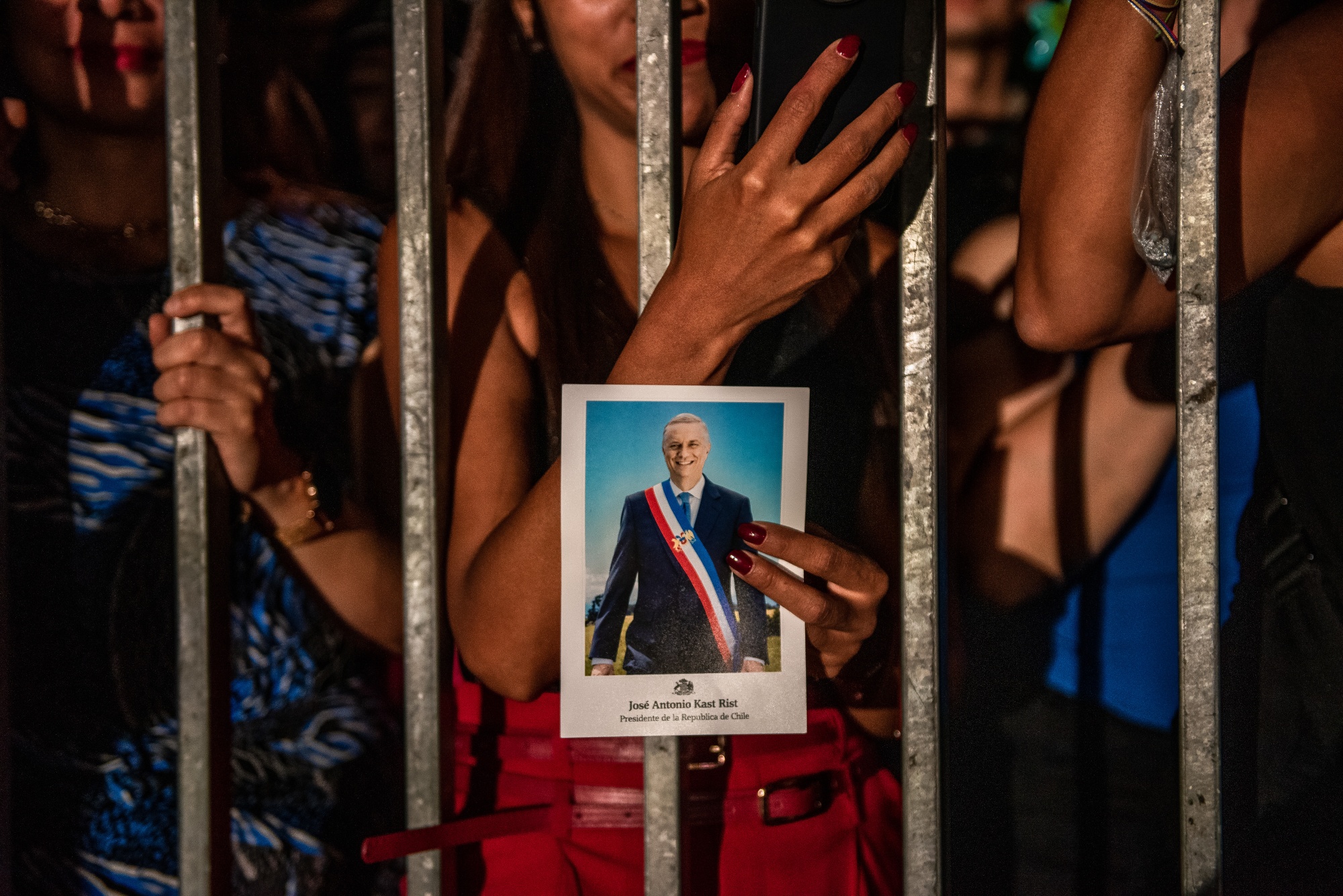 An attendee holds the official portrait of Jose Antonio Kast, Chile's president, in Plaza de la Ciudadania following the presidential inauguration ceremony of Jose Antonio Kast at La Moneda palace in Santiago, Chile, on Wednesday, March 11, 2026. Jose Antonio Kast signed decrees to ramp up border security, audit spending and cut red tape before delivering a tightly scripted inaugural speech on Wednesday night, underscoring his priorities at the helm of Latin America's most prosperous nation. Photographer: Cristobal Olivares/Bloomberg 