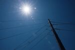 Power cables and a utility pole under the sun in a clear blue sky. Photographer: Bloomberg Creative Photos/Bloomberg Creative Collection