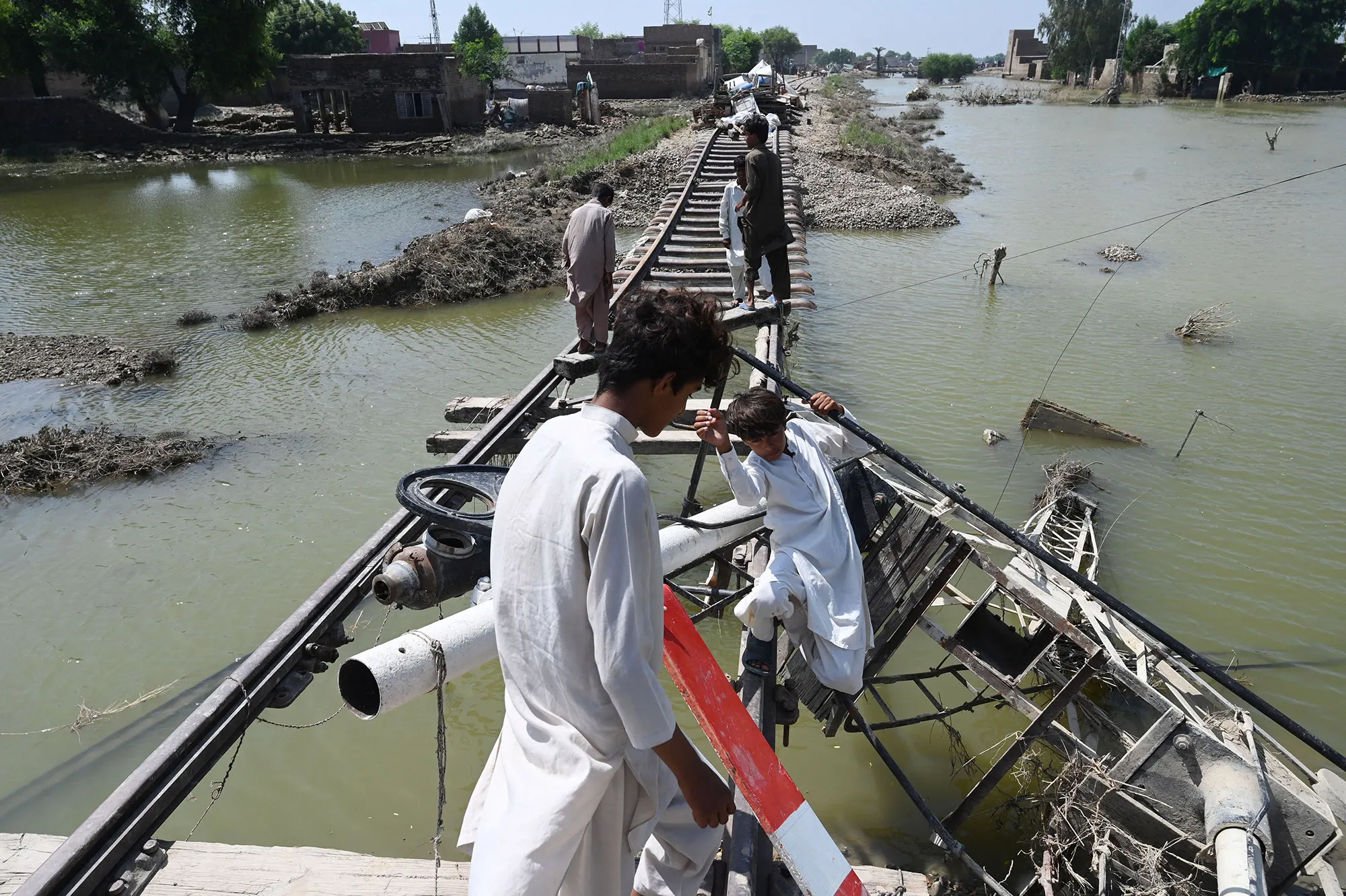 Residents cross a railway track damaged by flood waters in Fazilpur area, Punjab province, on Sept.&nbsp;3.