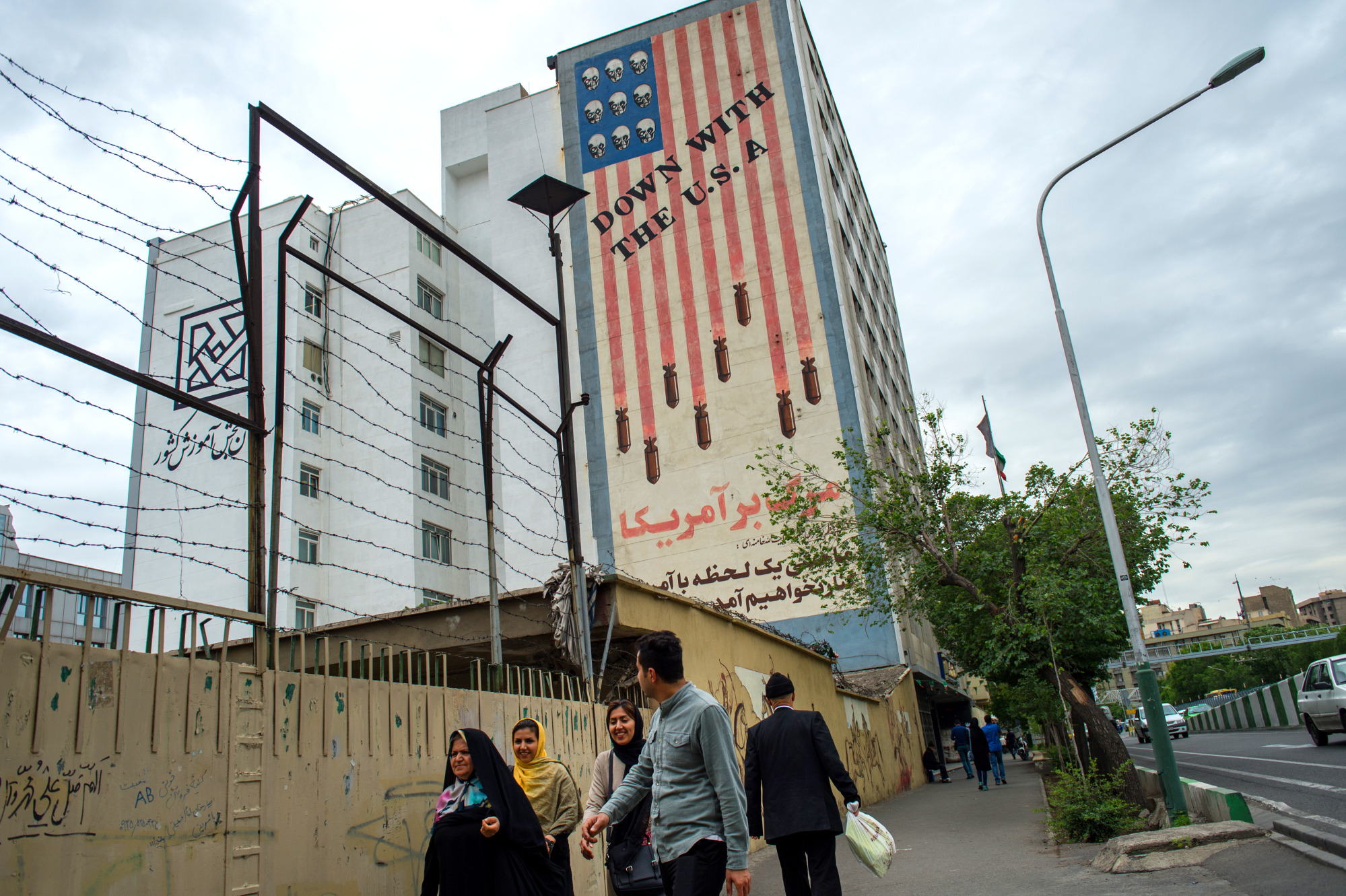 Pedestrians&nbsp;walk by a mural&nbsp;in Tehran.