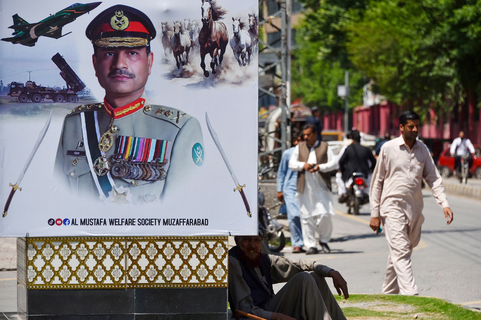 A man sits beside a poster featuring Pakistani Army Chief General Syed Asim Munir, along a road in Muzaffarabad, the capital of Pakistan-administered Kashmir, on May 14, 2025. The brief conflict between India and Pakistan last week may have left no clear victor, but Islamabad&#39;s generals are taking a win, riding a wave of approval on social media to burnish their recently tarnished image. (Photo by Sajjad QAYYUM &#x2F; AFP) (Photo by SAJJAD QAYYUM&#x2F;AFP via Getty Images) Photographer: SAJJAD QAYYUM&#x2F;AFP