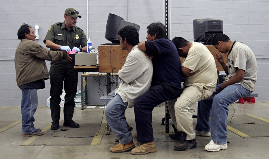 A man has his fingerprints electronically scanned by a U.S. Border Patrol agent while others wait for their turn at the U.S. Border Patrol detention center in Nogales, Arizona.