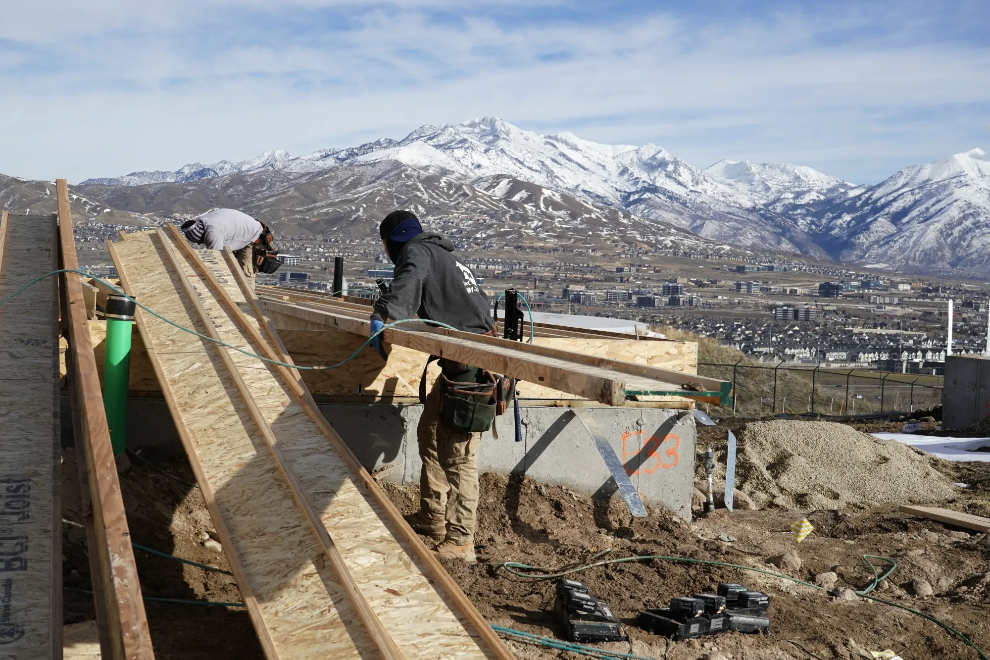 Workers install lumber to the exterior frame of a single family home in Lehi, Utah.