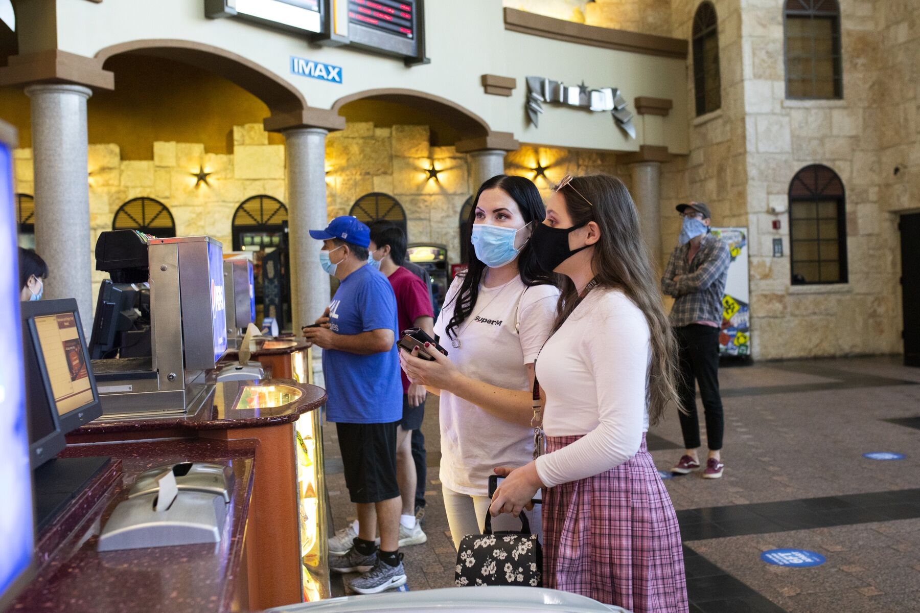 People wearing protective masks stand at a concessions counter at a Regal Cinemas theater in Austin, Texas, U.S., on Friday, Aug. 21, 2020. 