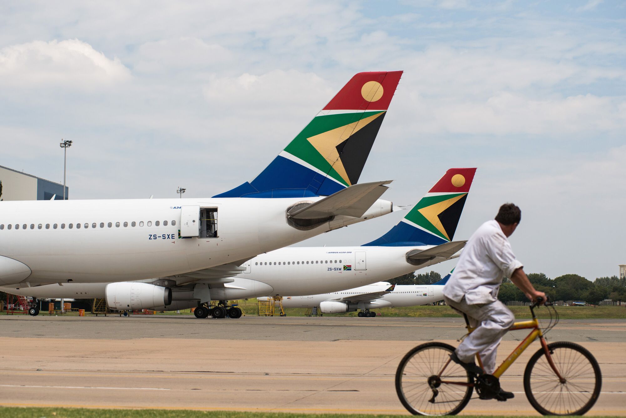 A man cycles past South African Airways branded aircraft at O.R. Tambo International airport in Johannesburg.