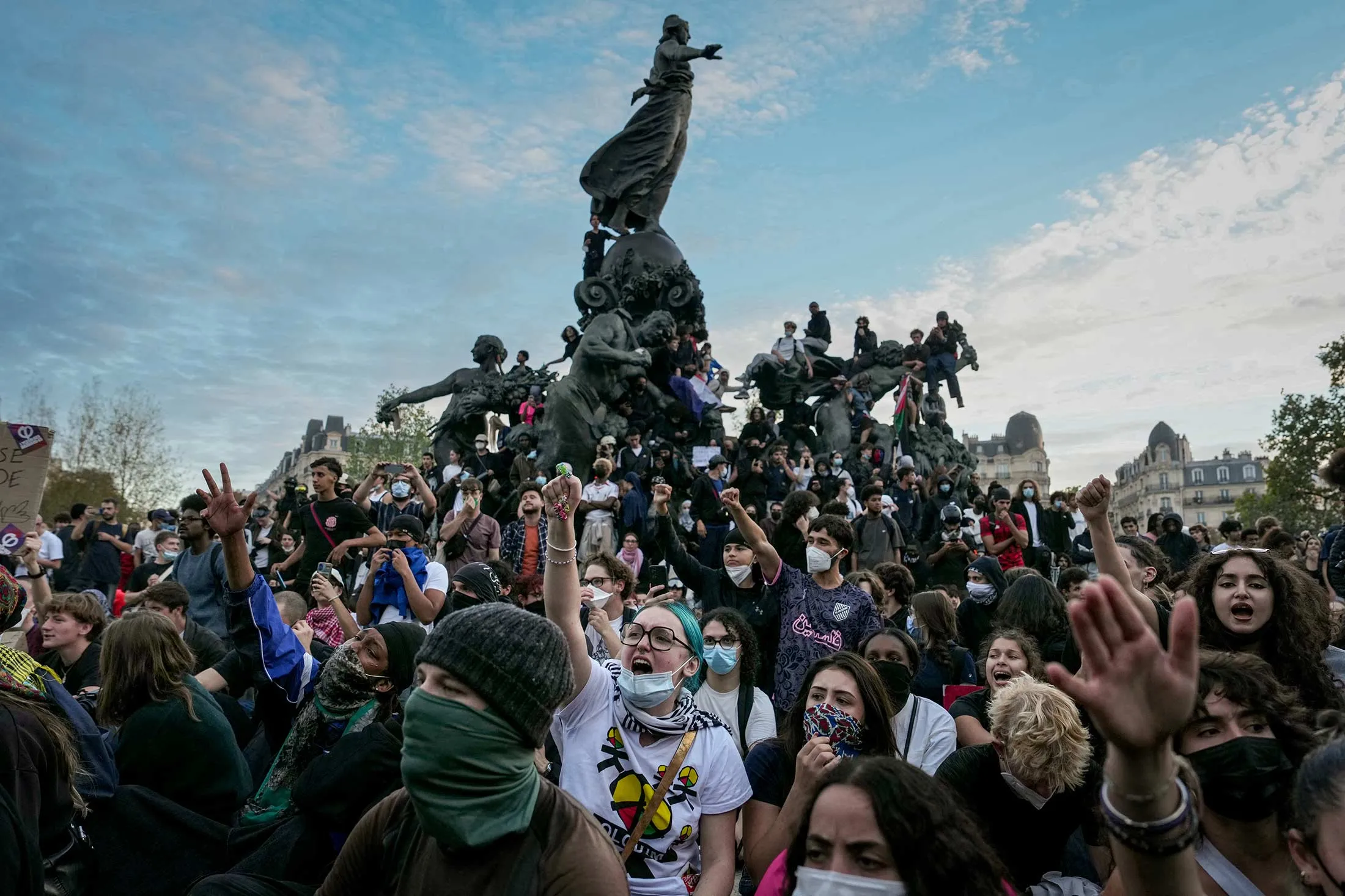 TOPSHOT - People gather on and around the statue in the center of the Place de la Republic square in Paris at the end of a demonstration by high-school students, joined by unions and teachers.