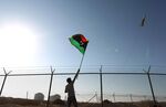 A man waves a Libyan flag as fighter jet flies past.