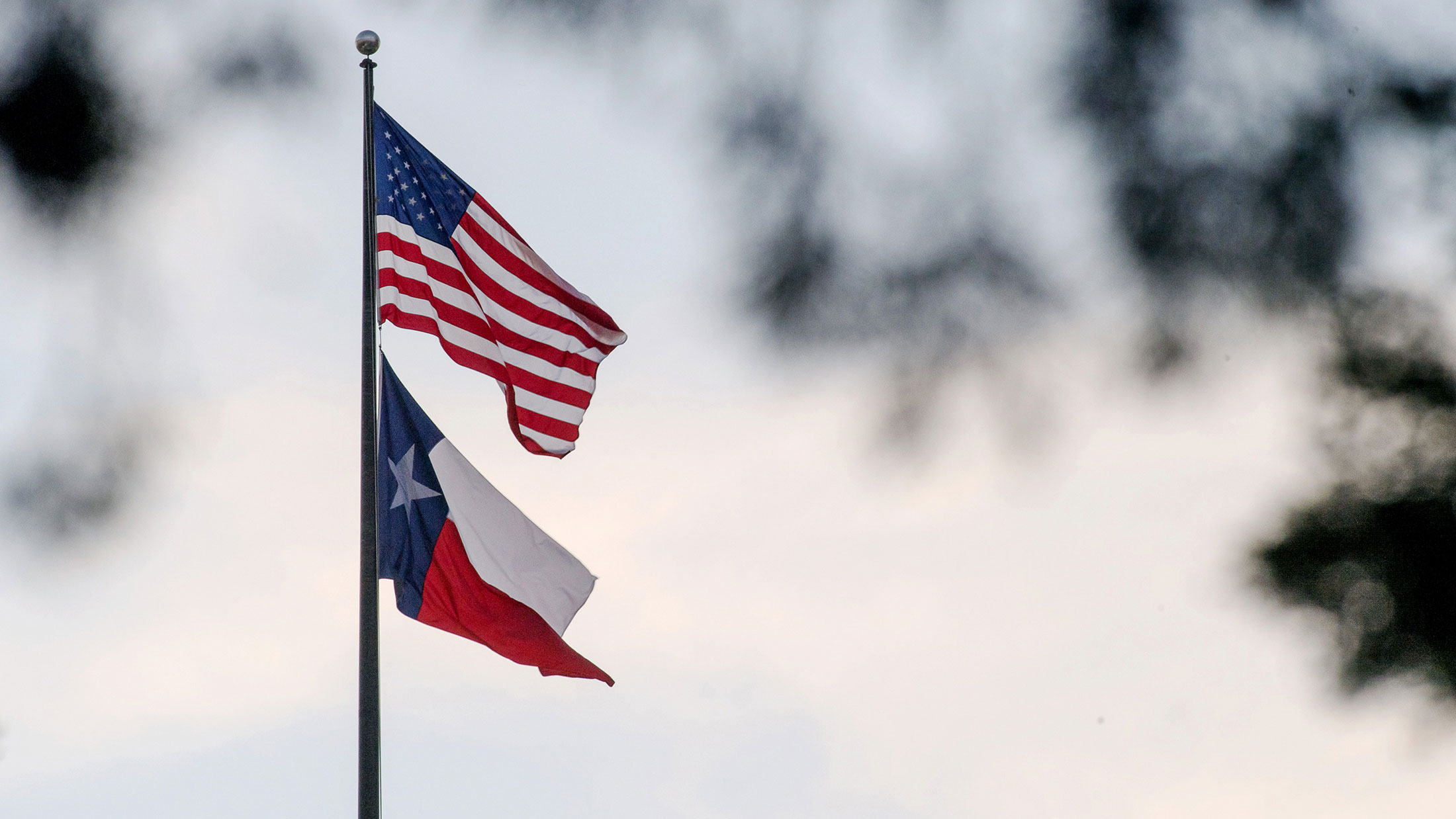 An American flag flies with the Texas state flag outside the Texas State Capitol building in Austin on March 14, 2017.
