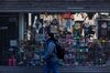 A pedestrian wearing a protective mask passes in front of a souvenir shop temporarily closed in the Times Square area of New York, U.S.