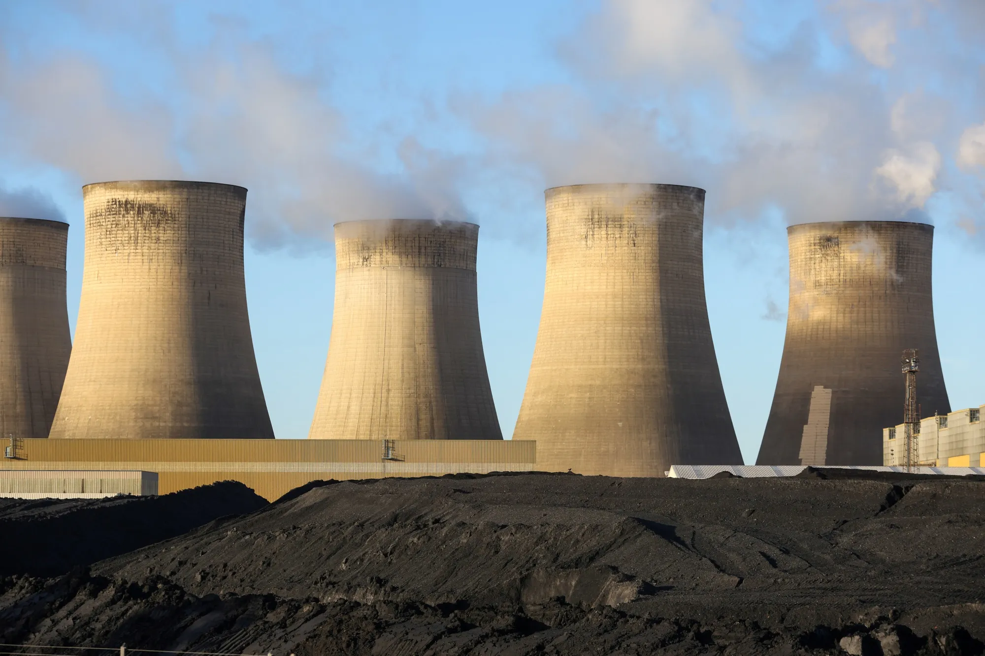 Piles of coal next to cooling towers at Uniper SE's coal-fired power station in Ratcliffe-on-Soar, U.K.&nbsp;on Thursday, Dec. 2, 2021.