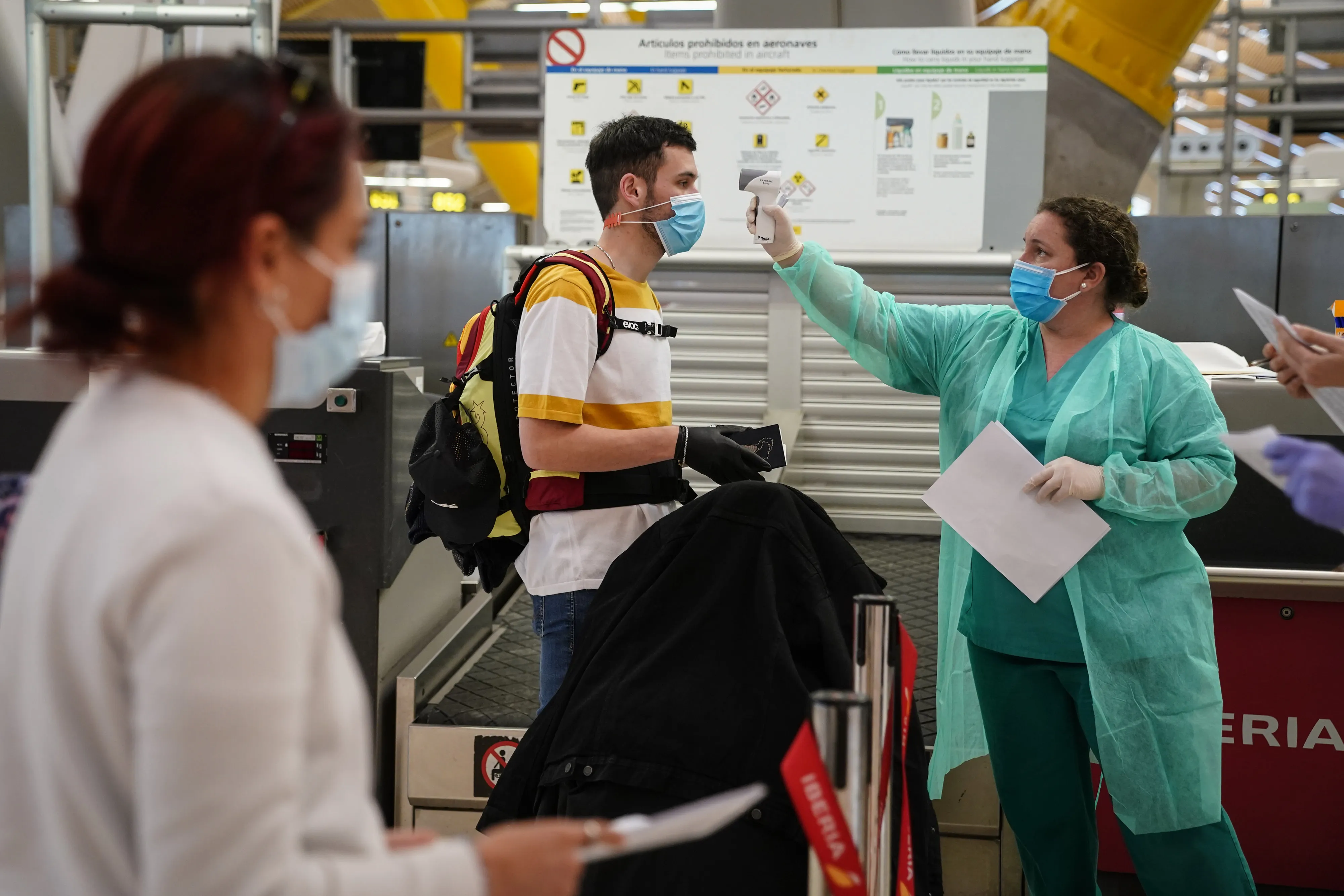A medical worker checks the temperatures of a passenger at Madrid Barajas airport.
