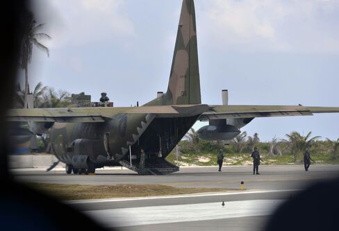 Members of the Taiwan coast guard stand guard around a C-130 transport plane on Itu Aba island in the Spratlys chain.
