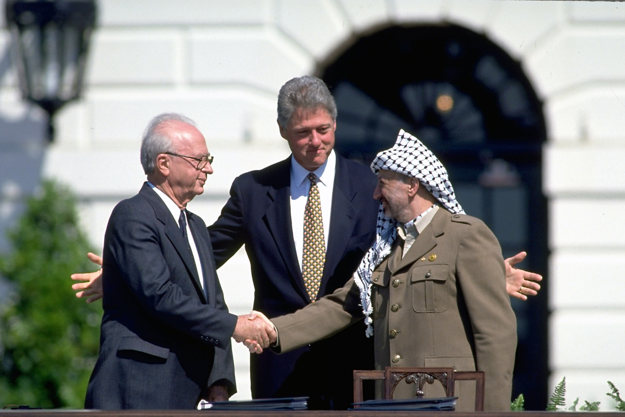 Pres. Clinton (C) smiling as PLO chmn. Yasser Araf