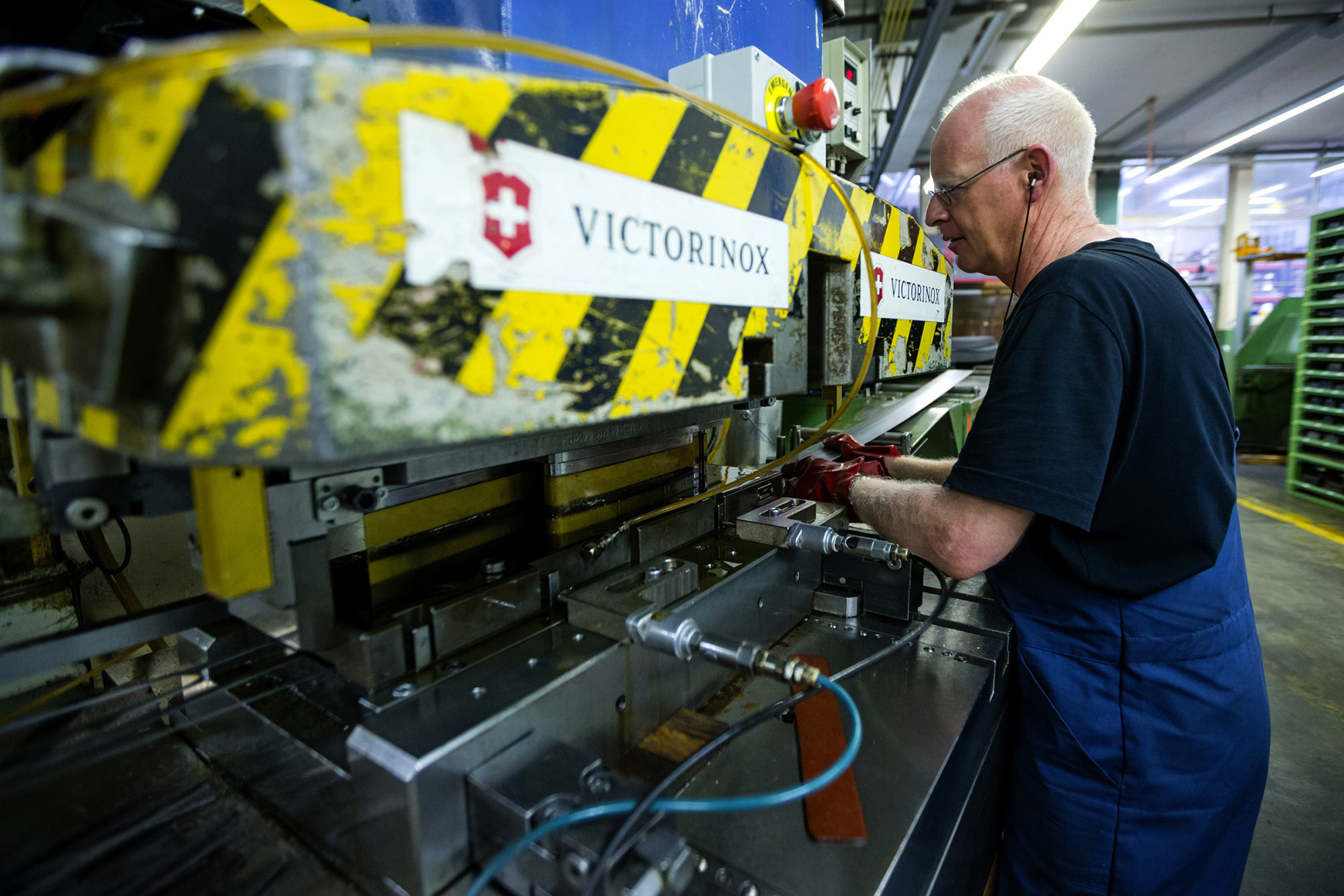 An employee feeds a sheet of steel into a cutting machine to make the blades of Swiss Army knives, produced by Victorinox AG, at the company's manufacturing plant in Ibach, Switzerland, on Tuesday, September 9, 2014. The Swiss National Bank's three-year-old cap on the franc has helped the economy outperform that of the euro area in nine of the last 12 quarters.
