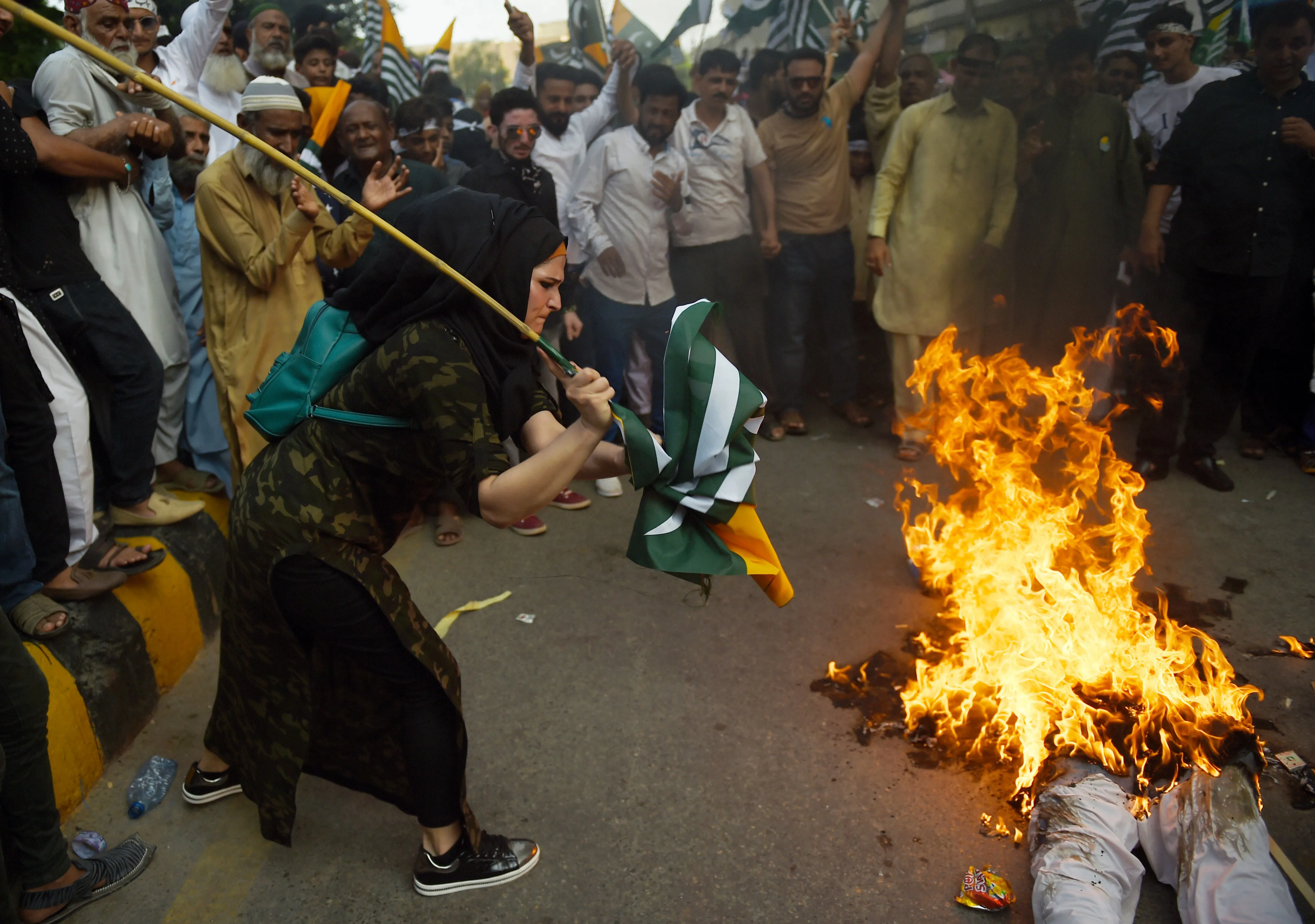 A woman beats a burning effigy of Indian Prime Minister Narendra Modi during an anti-India protest rally in Karachi on Aug. 25.