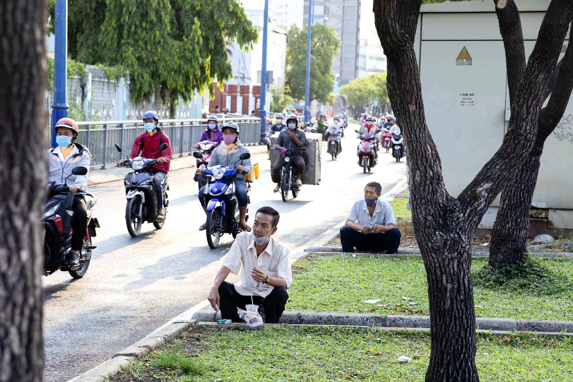 Motorcyclists ride past men wearing face masks during a partial lockdown imposed due to the coronavirus in Ho Chi Minh city, Vietnam on April 1.