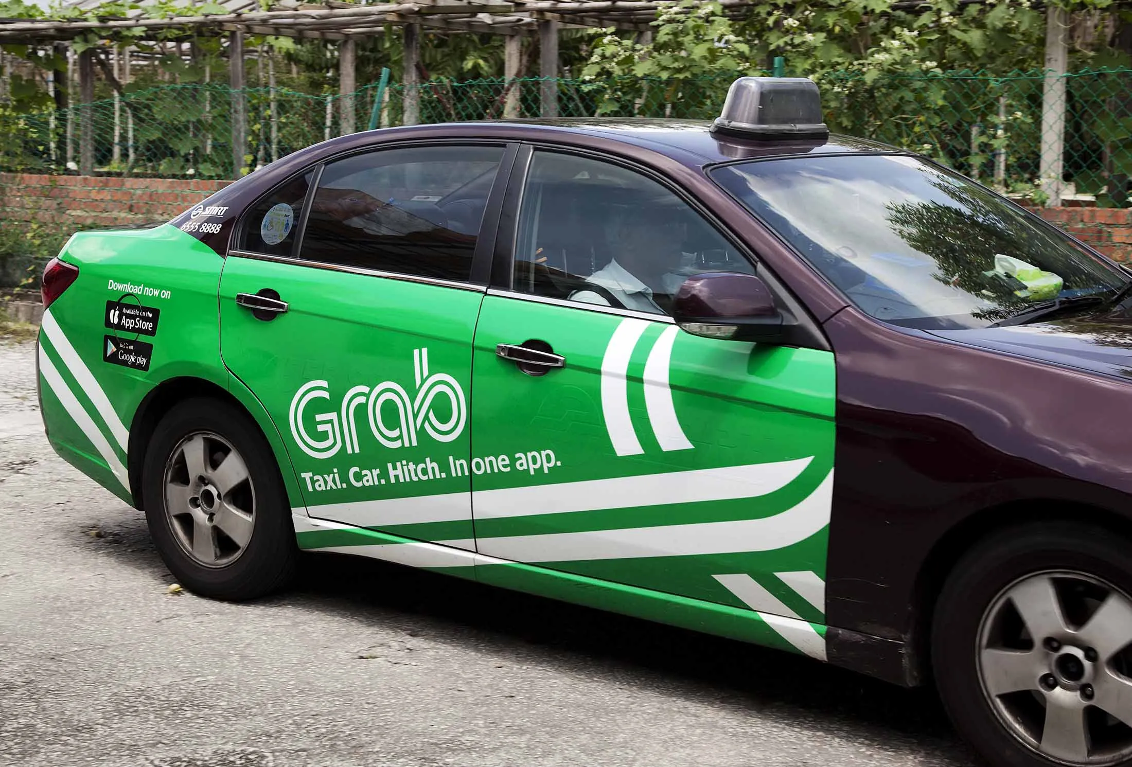A Strides Transportation Pte taxi, operated by SMRT Corp., displays an advertisement for the ride-hailing application Grab, operated by GrabTaxi Holdings Pte, in Singapore, on Tuesday, July 12, 2016.
