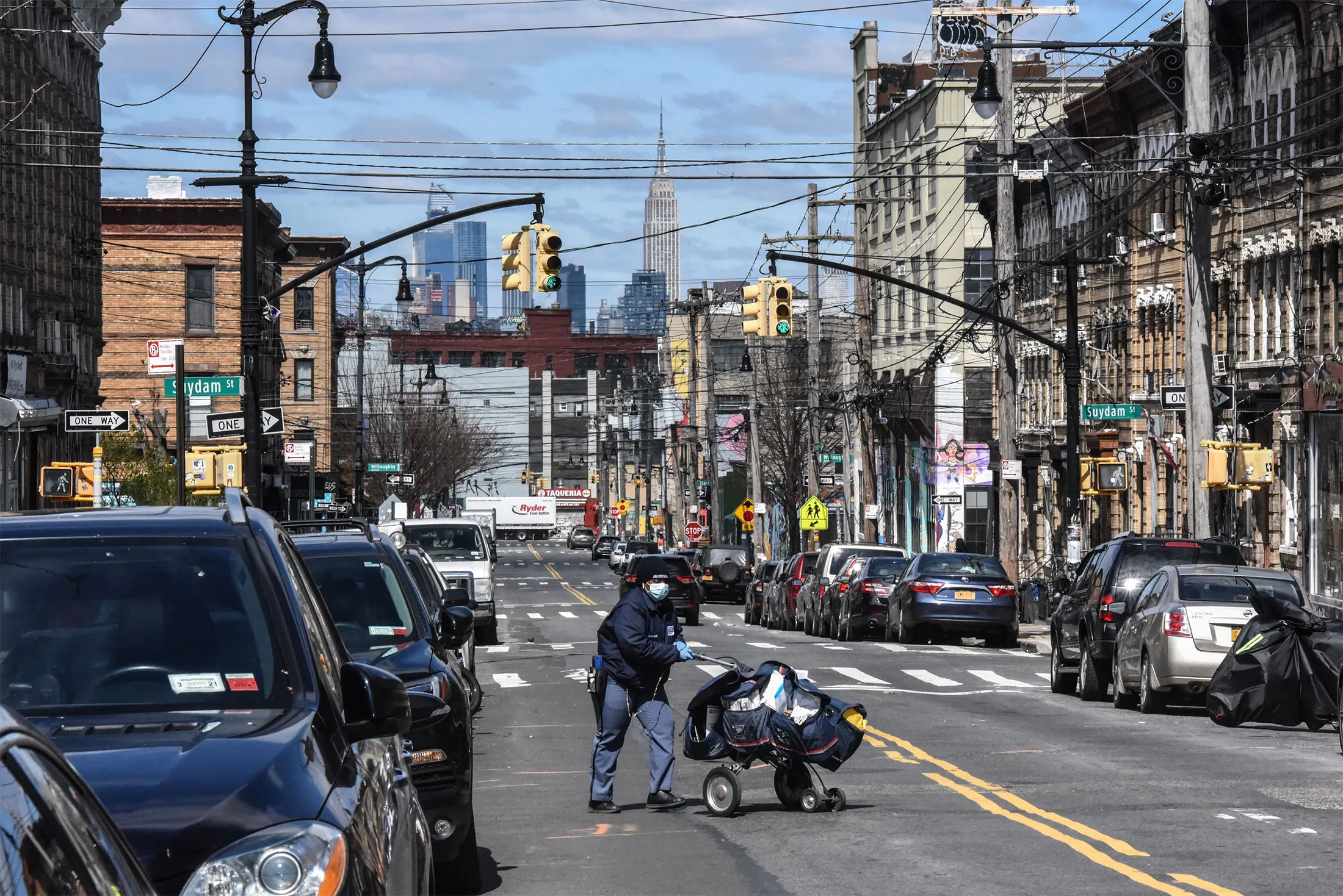 A mail carrier crosses an empty Wyloff Ave. in the Bushwick neighborhood of Brooklyn in April.