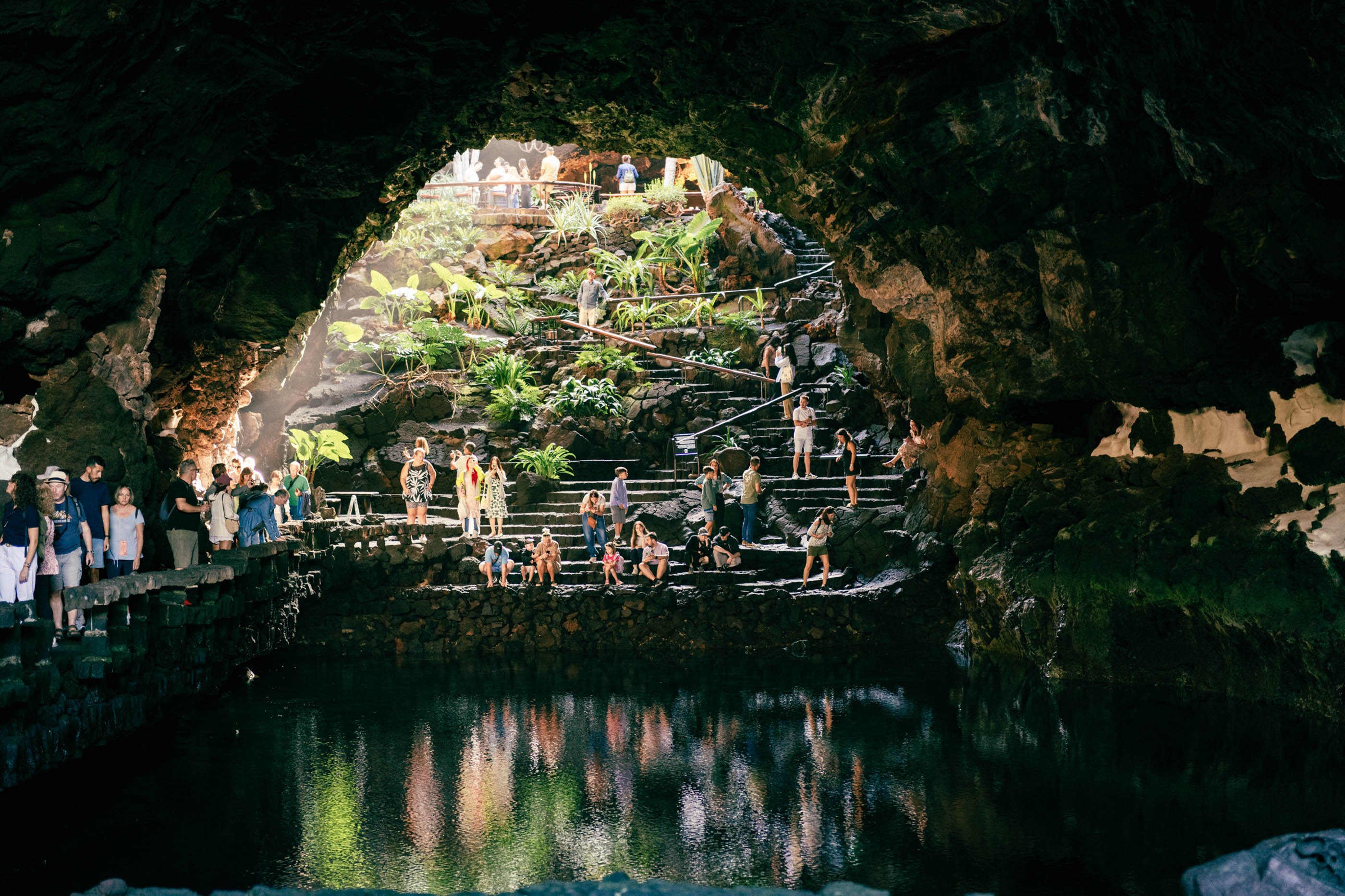 Visitors on the stone steps of the underground salt lake of Jameos del Agua, part of a volcanic tunnel system in Lanzarote.