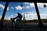 A cyclist passes the Eiffel Tower in Paris, which has been working aggressively to curb the use of private cars. But these efforts have not come without controversy and backlash.
