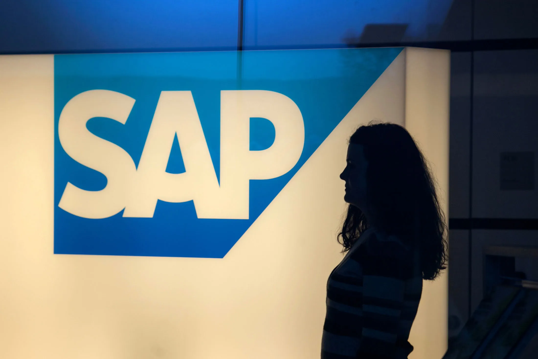 A visitor passes an illuminated SAP logo in Walldorf, Germany.
