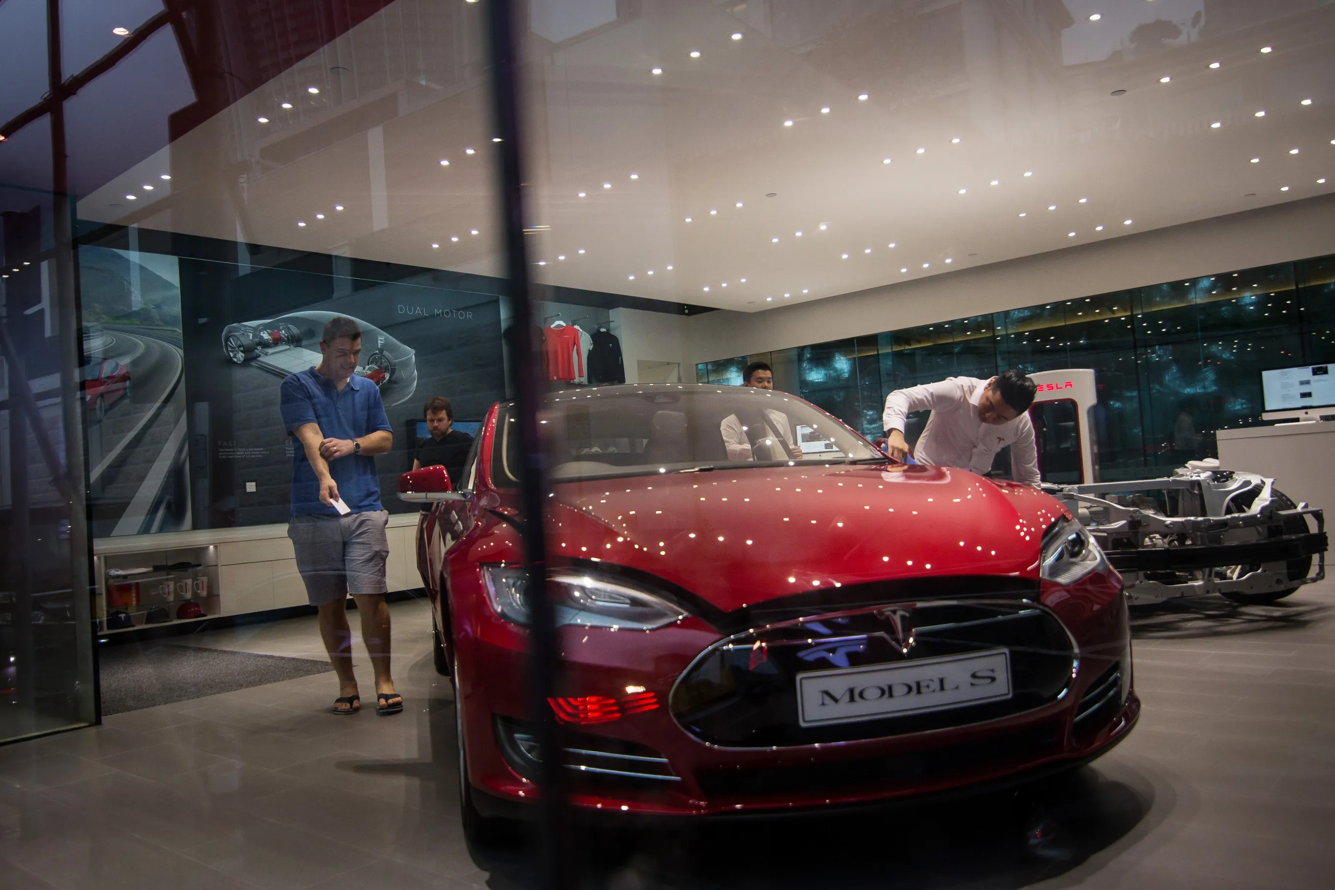 Customers look at a Tesla Motors Inc. Model S electric vehicle at the company's showroom in&nbsp;Hong Kong.