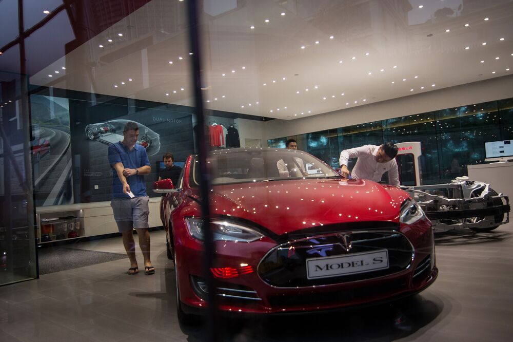 Customers look at a Tesla Motors Inc. Model S electric vehicle at the company's showroom in Hong Kong.