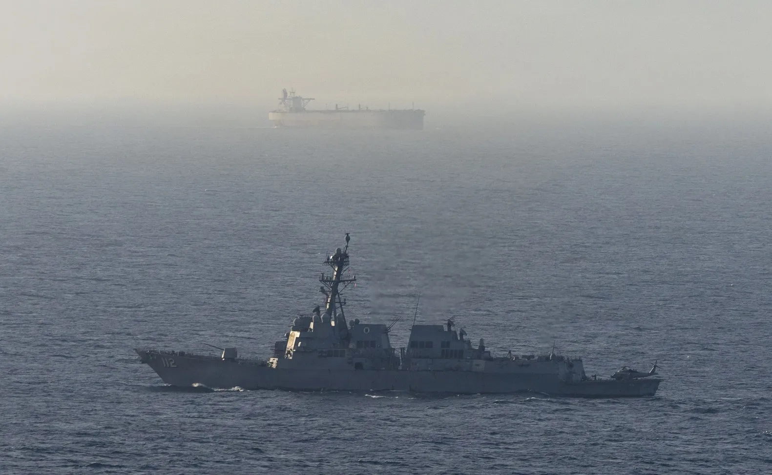 A guided-missile destroyer patrols the Arabian Sea near a cargo ship, in a photo released by the US Navy, on&nbsp;April 15.