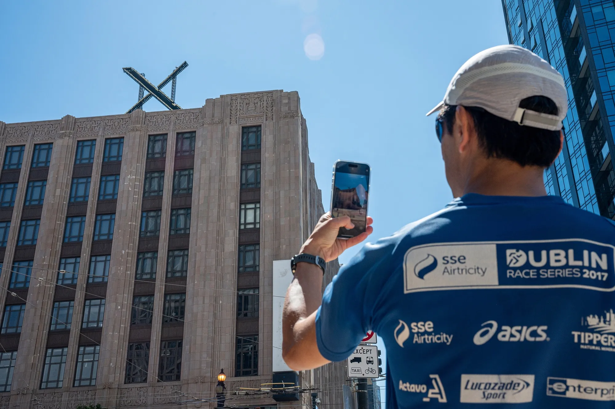 A pedestrian takes a photograph of the new Twitter X logo at the company's headquarters in San Francisco on Saturday.