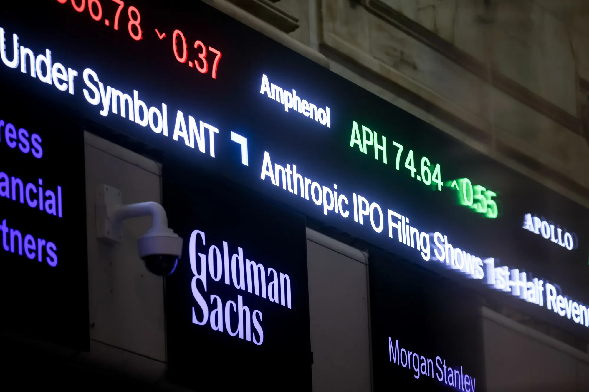 A news ticker displays Anthropic IPO news on the floor of the New York Stock Exchange.
