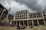 Pedestrians sit outside the London Stock Exchange.
