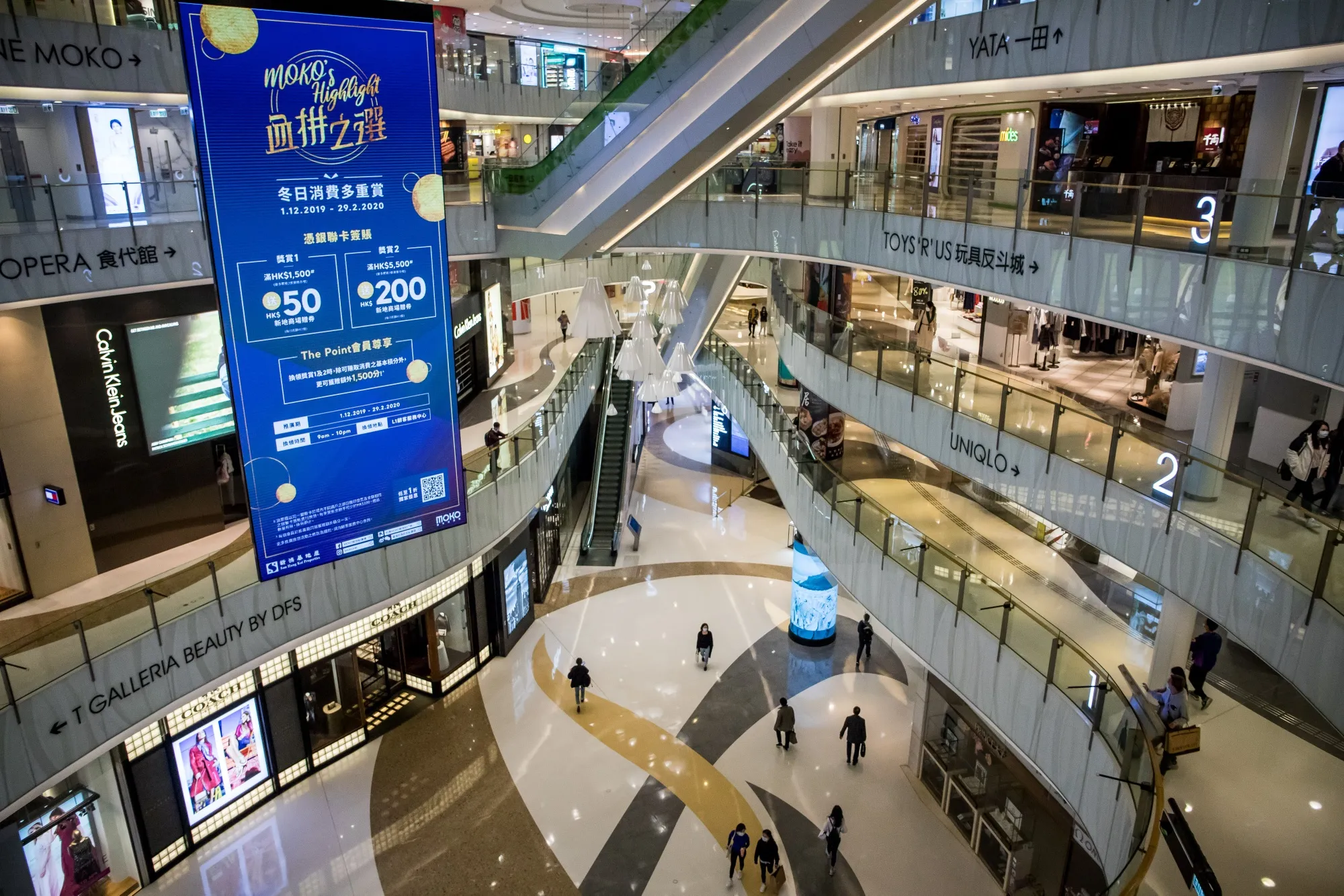 Shoppers wearing protective masks walk through a shopping mall in&nbsp;Hong Kong.