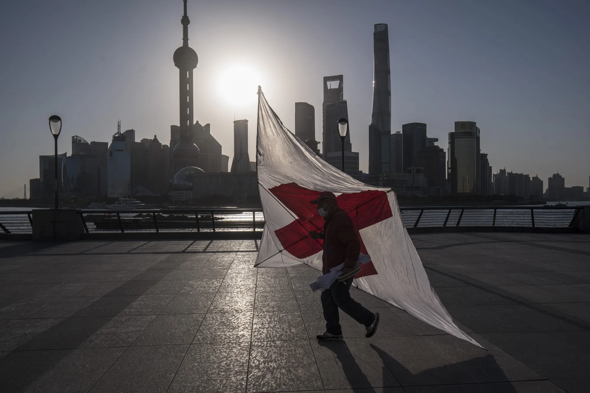 A man carries a kite&nbsp;along the Bund as skyscrapers of the Pudong Lujiazui Financial District stand in Shanghai on March 20.