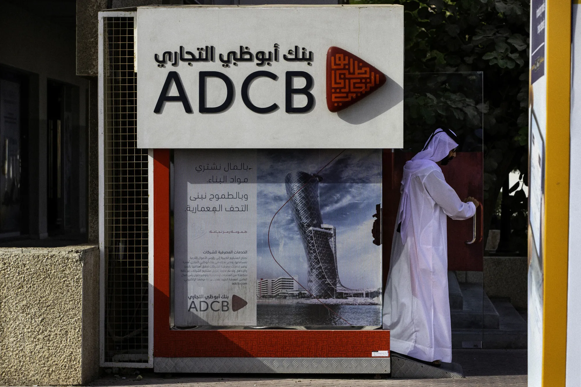 An Emirati man exits after using an Abu Dhabi Commercial Bank PJSC&nbsp;bank automated teller machine&nbsp;in Dubai.