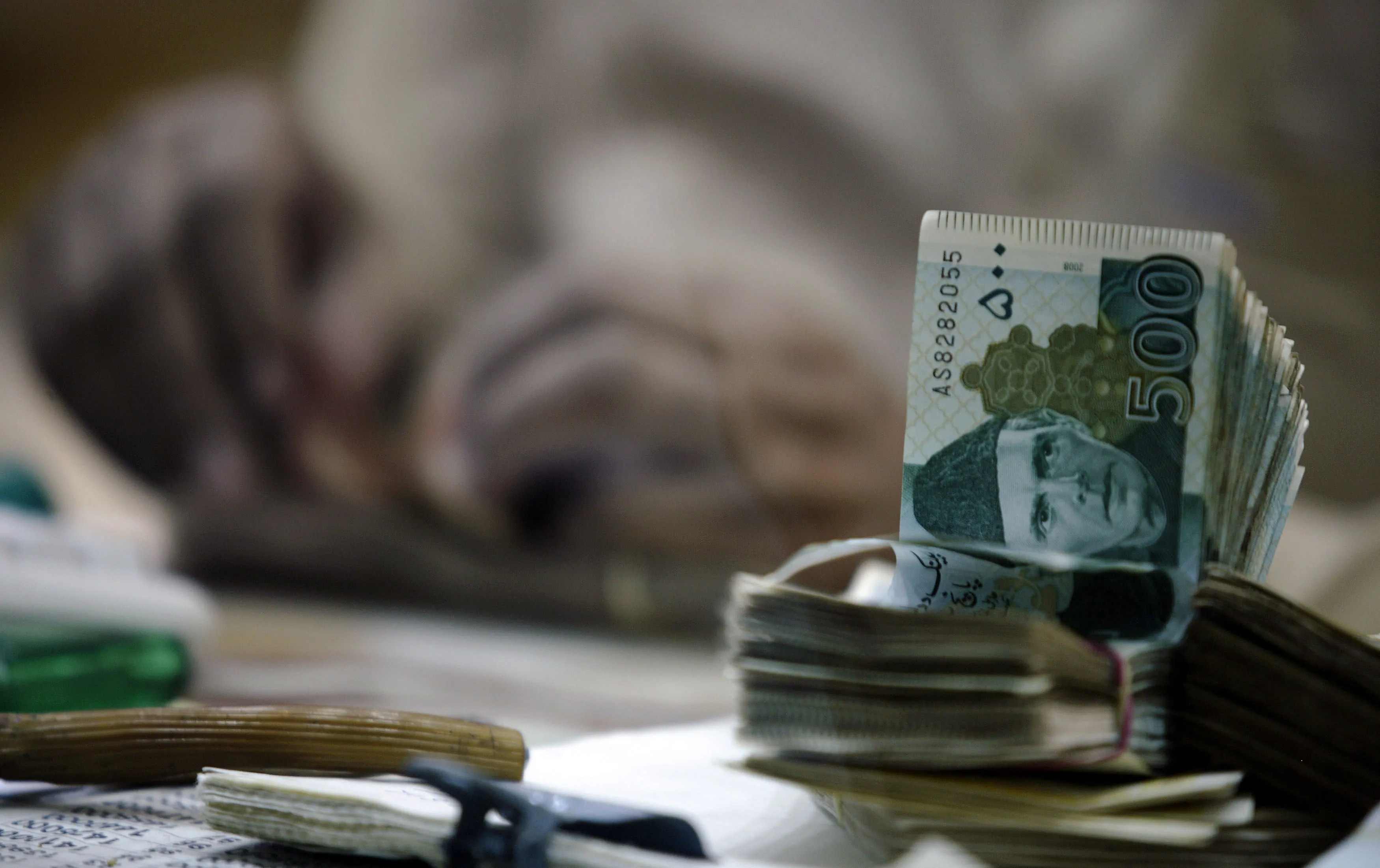 An employee counts out rupee banknotes&nbsp;in Karachi, Pakistan.&nbsp;