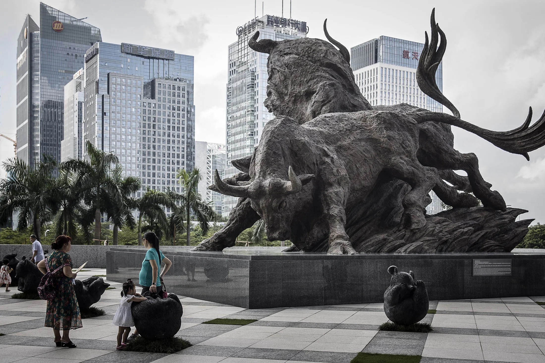 People stand in front of a sculpture of bulls at the entrance to the Shenzhen Stock Exchange building in Shenzhen, China, on Tuesday, Aug. 23, 2016. Derivative markets are pointing to renewed bets on yuan depreciation, with a three-month measure of expected price swings poised for the biggest monthly increase since January.
