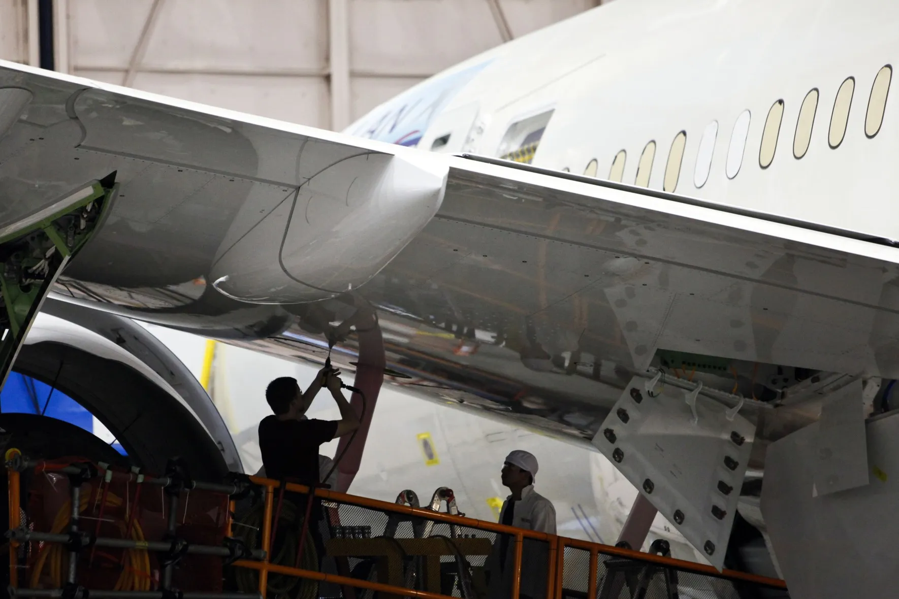 Employees work underneath the wing of a Boeing Co. 787 during final assembly of the airplane at the company’s&nbsp;factory in Everett, Washington.