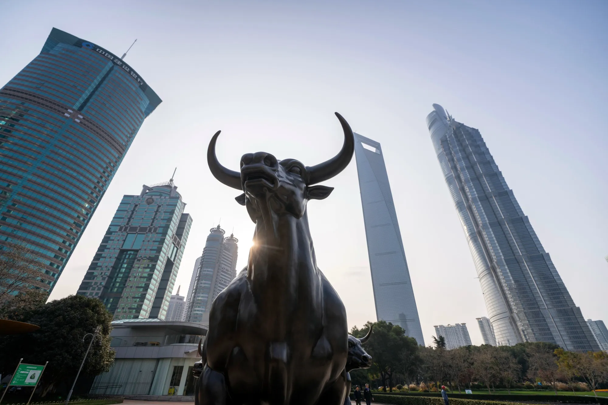 A statue of a bull in front of buildings in the Lujiazui financial district in Shanghai, China.