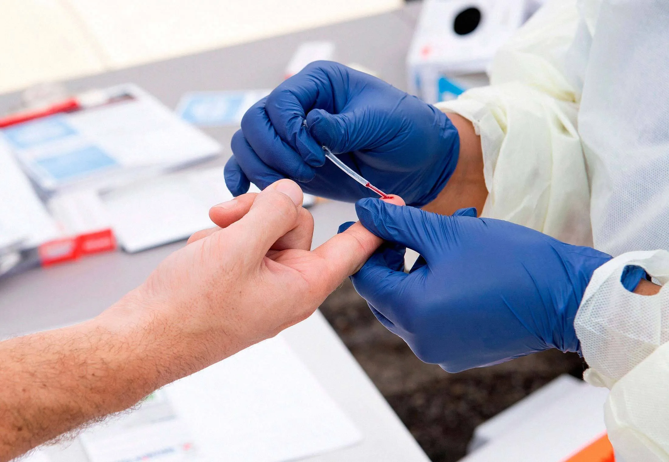 A health worker takes a drop of blood for a Covid-19 antibody test.