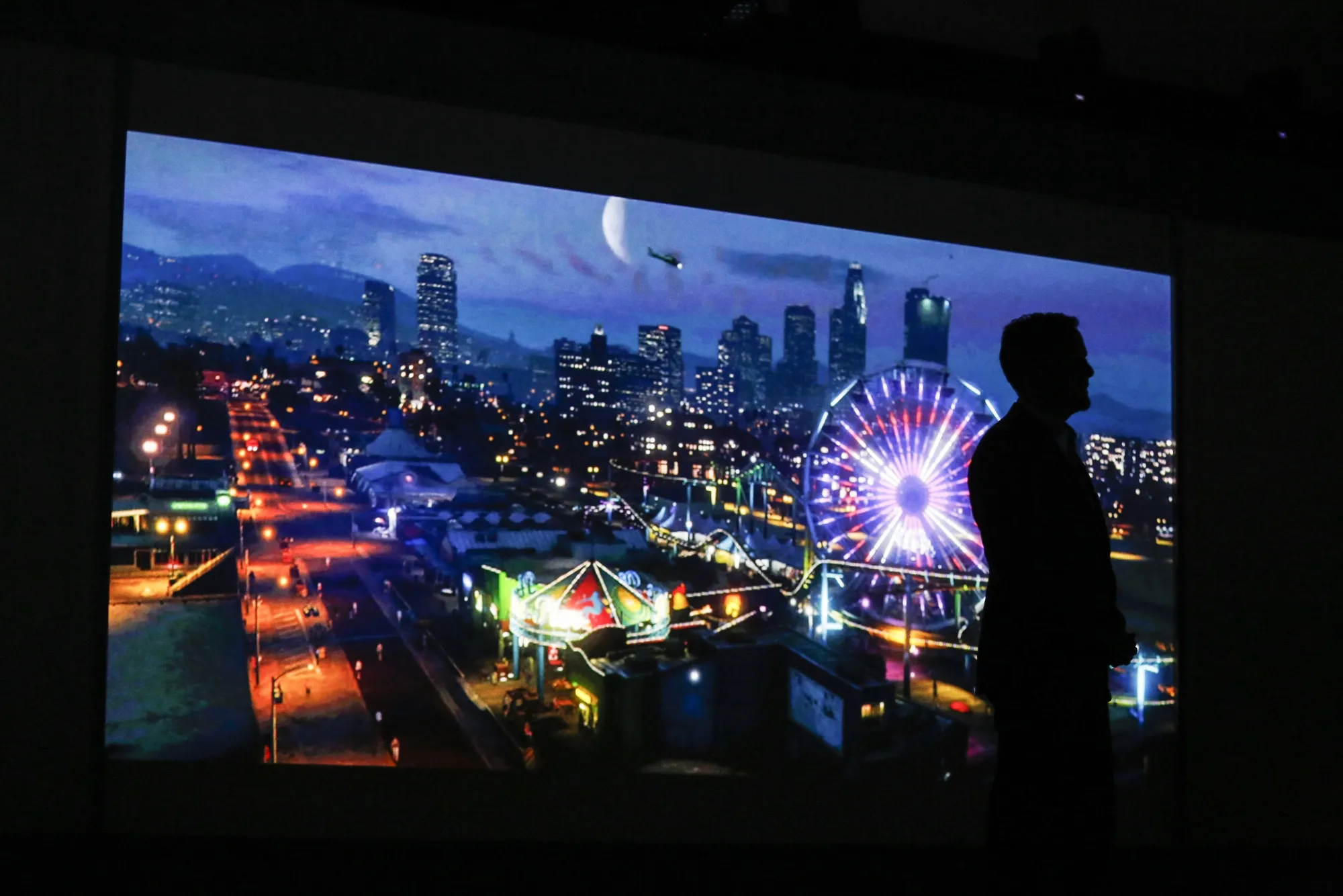 Andrew House, president and chief executive officer of Sony Computer Entertainment Inc., is silhouetted as he watches a trailer for Grand Theft Auto 5 in 2014. The game is set in a realistic simulation of Los Angeles.